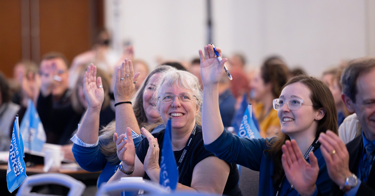 Image of Delegates holding hands up and clapping.
