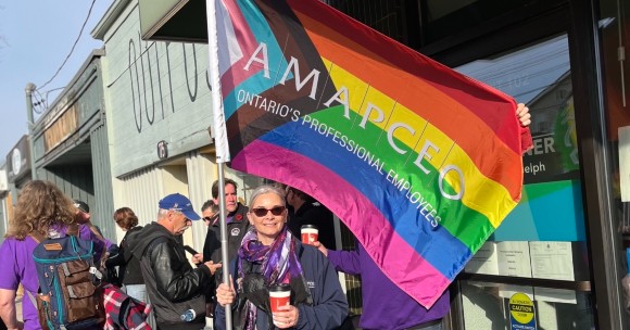 Suzanne Conquer waving an AMAPCEO pride flag at a CUPE support demonstration