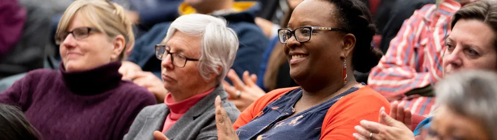 A photo of a crowd of AMAPCEO members smiling and clapping