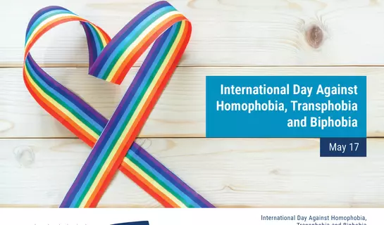 Image of a rainbow ribbon placed on a wooden deck to represent International Day Against Homophobia, Transphobia and Biphobia
