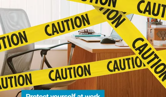 Caution tape in from of desk with text "Workplace hazards can be anywhere