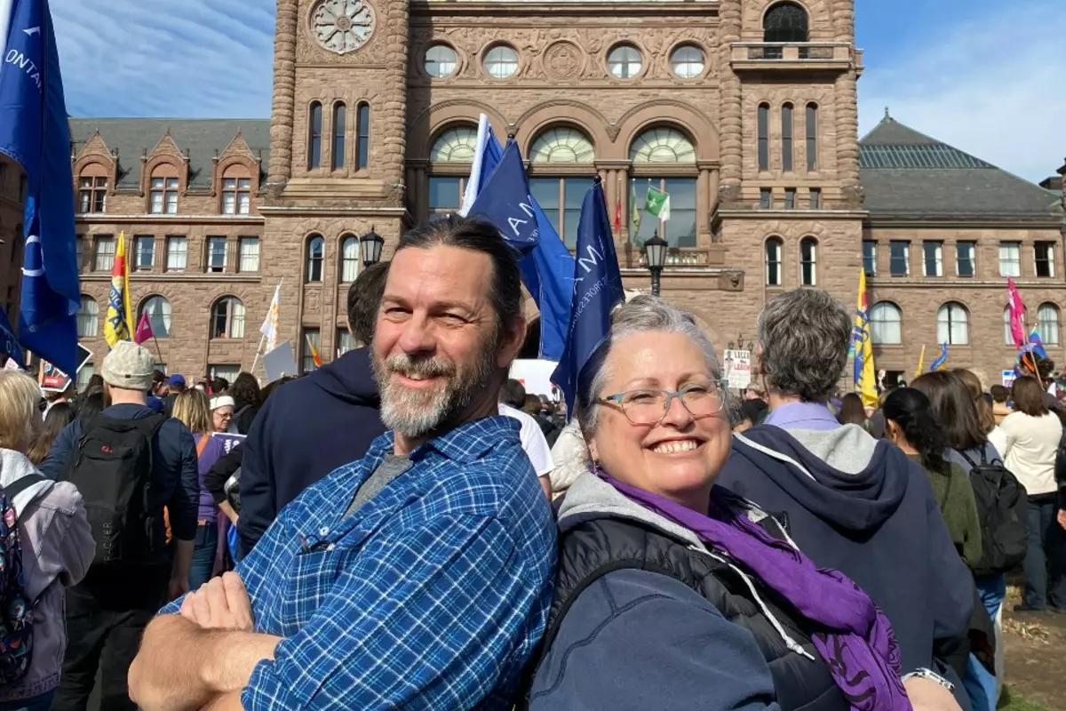An AMAPCEO activist and Vice-President Cynthia Watt standing back to back in front of Queen's Park