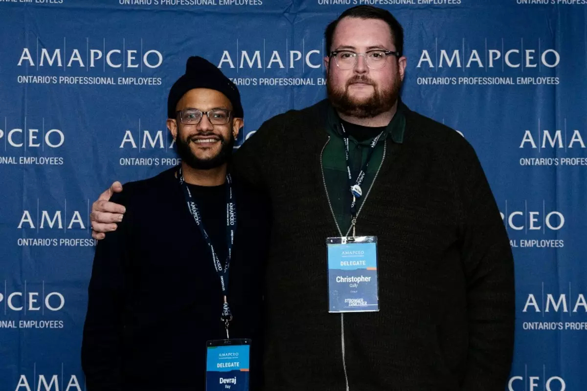 Chris Cully and Devraj Ray in front of AMAPCEO banner