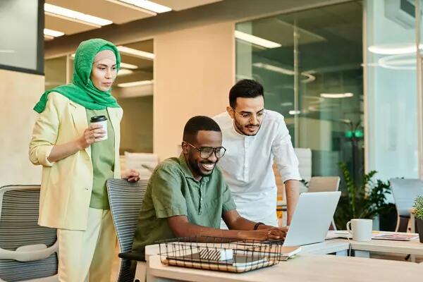 A group of smiling people looking at a laptop