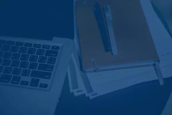 A laptop, notebook, pens, and paper