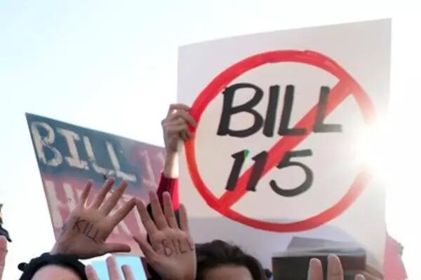 A sign with "Bill 115" in the centre of a red circle with a line through it