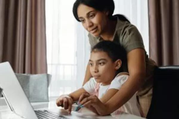 An image of a mother helping her daughter use a laptop