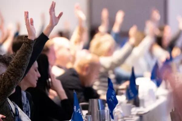 members raising hands at a conference