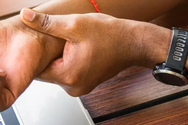 image of someone holding their wrist in front of their laptop