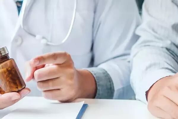 Image of two sets of hands, one holding a pill container