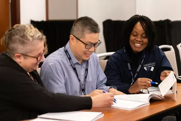 Three AMAPCEO members smiling and looking at documents