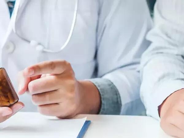 Image of two sets of hands, one holding a pill container