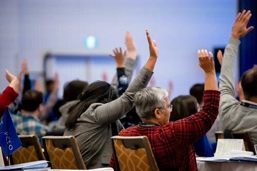 A group of AMAPCEO Delegates raising their hand to vote 