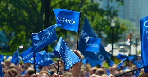 A crowd waving small AMAPCEO flags