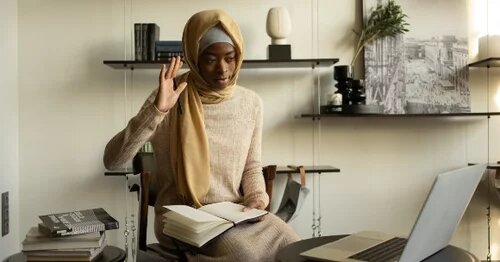 image of person in front of a laptop raising their hand