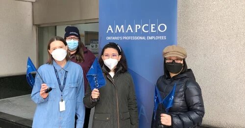 Photo of several masked AMAPCEO members holding AMAPCEO swag