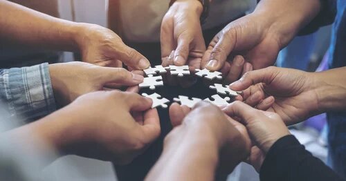 Image of hands holding puzzle pieces in a group