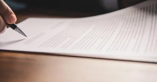 Image of hand with pen on document