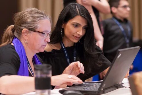 An AMAPCEO Workplace Representative is helping a fellow member. They are both sitting at a laptop.