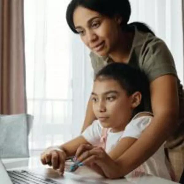 An image of a mother helping her daughter use a laptop