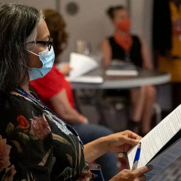 A masked member reading the agenda at AMAPCEO's WPR conference in 2022
