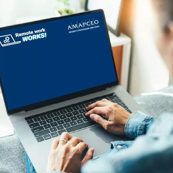 A person at a laptop with the AMAPCEO Remote Work WORKS! Virtual Background on the screen.